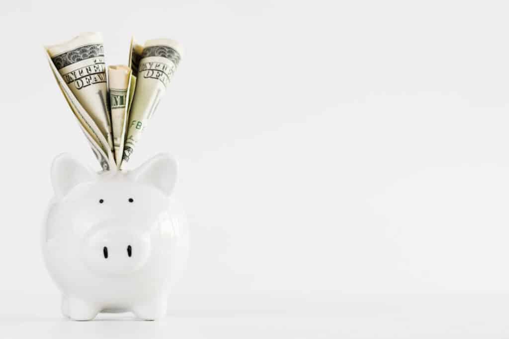 America dollars banknotes money into piggy bank on white background. Saving money wealth and financial concept.